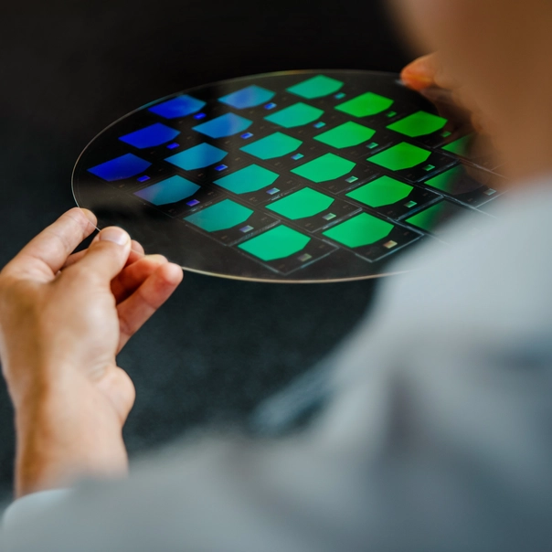 A close-up image of an ultra-flat, lightweight waveguide lens refracting light into a rainbow