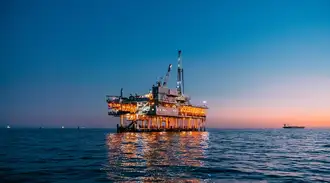 Offshore oil platform illuminated at sunset in open sea