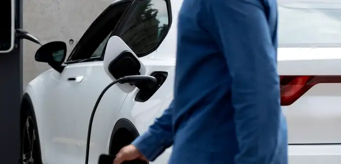 Person charging an electric car at a public charging station