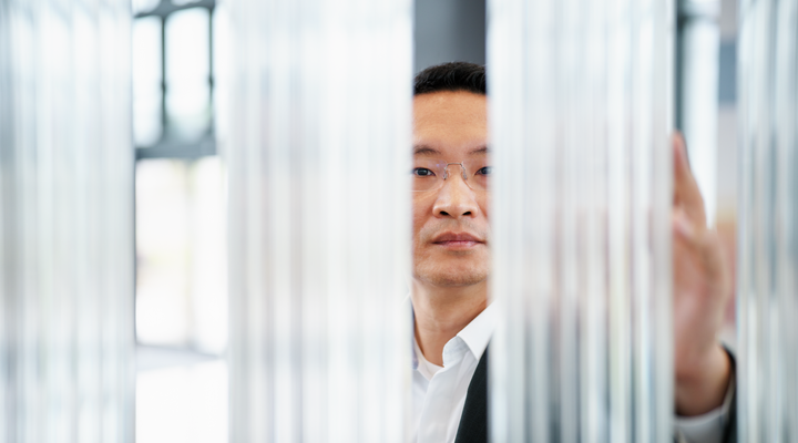 Person examining vertical glass rods or optical components in a bright lab or showroom setting