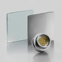 A metallic circular connector with gold pins, positioned near glass and metal square plates.