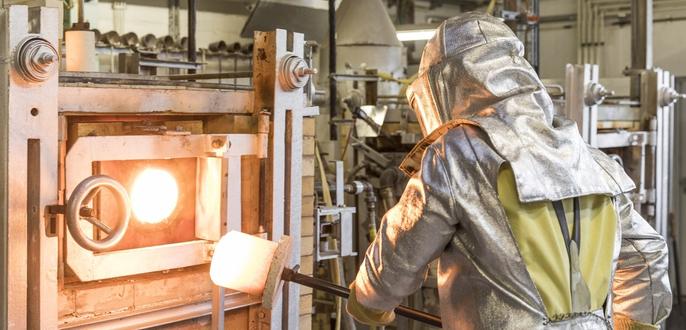 A SCHOTT employee wears protective gear to operate the hot glass melting production