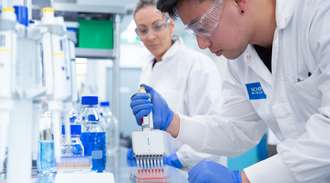 两名身穿实验服的生物科学家在实验室中测试微流体试剂。