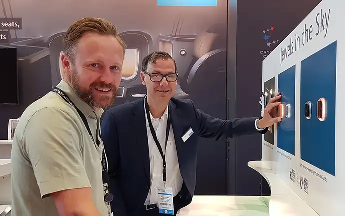 Ben Rowan and Philip Fischer touching the Jade Reading Light displayed at the SCHOTT booth at Aircraft Interiors Expo 2022