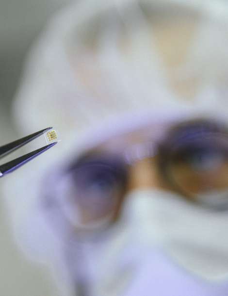Researcher holding a miniaturized glass-sealed microelectronic component with tweezers