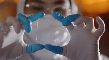 Person with medical face mask and gloves holding precious geometric reflective waveguide.