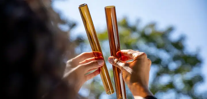 Hands holding up two tubes of amber glass