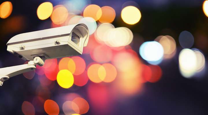 A CCTV security camera at night with blurred coloured lights in background