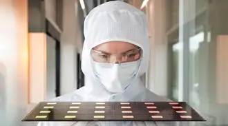 A woman in cleanroom clothing carries a tray with several chips.