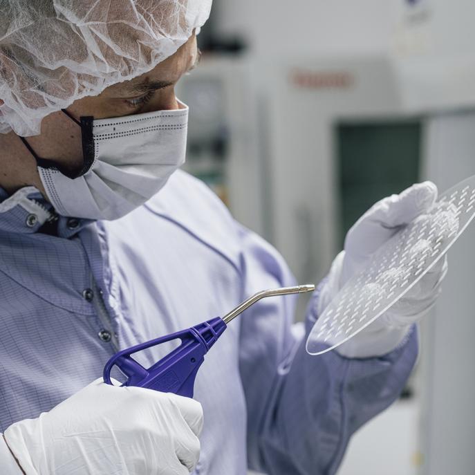 Photo showing a person in a cleanroom inspecting a wafer