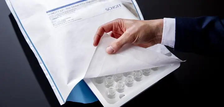 A hand opens up a SCHOTT iQ® Integribag displaying nested vials