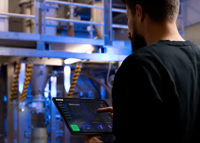 An engineer uses a tablet to control various production parameters in a manufacturing facility.