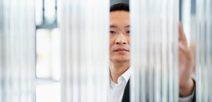 Person examining vertical glass rods or optical components in a bright lab or showroom setting