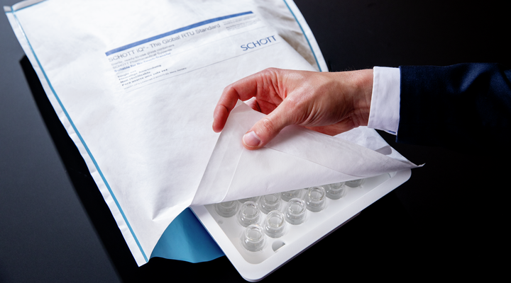 A hand opens up a SCHOTT iQ® Integribag displaying nested vials