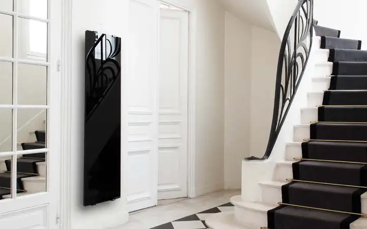 Shiny black glass wall heater with printed heating circuits in a hallway