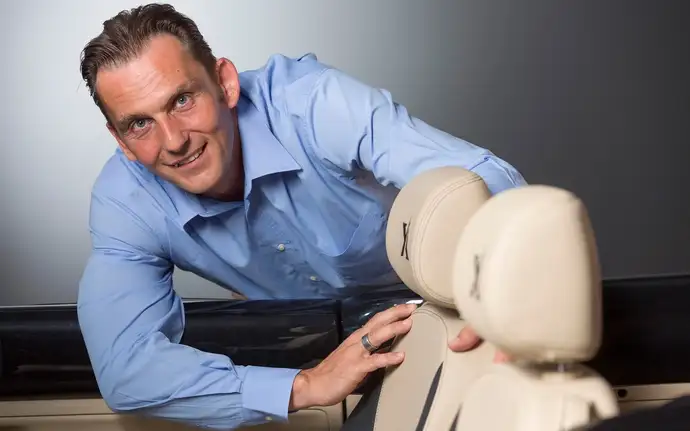 Marjan Trobis bends over leather seats of a car