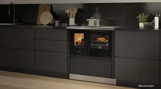 A sleek black kitchen setup featuring a modern stove with a visible oven cooking chicken and a lit fire chamber beside it.