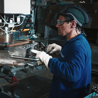  A man wearing white gloves and protective goggles operates a machine during AR waveguide manufacturing.