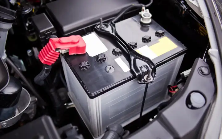 A close-up view of a start-stop battery installed in an engine bay of a car.