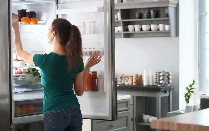 Woman taking food out of fridge at home