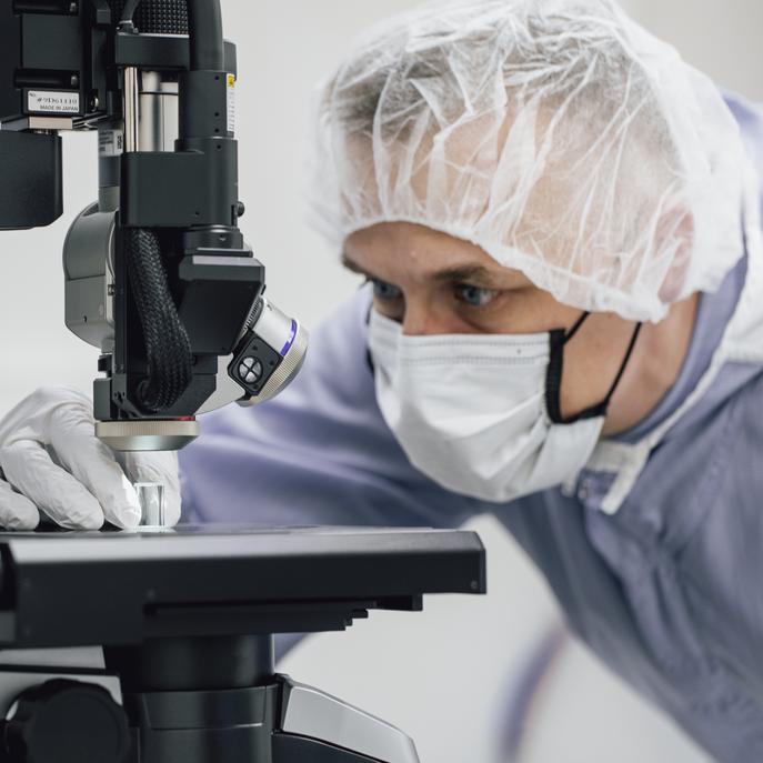 Photo of a laboratory employee putting a sample under the microscope. 