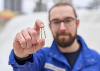 Marius Amschler stands in front of a cullet warehouse and holds a vial up to the camera