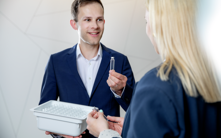 Man showing a pharmaceutical glass cartridge to a woman holding a nest of cartridges