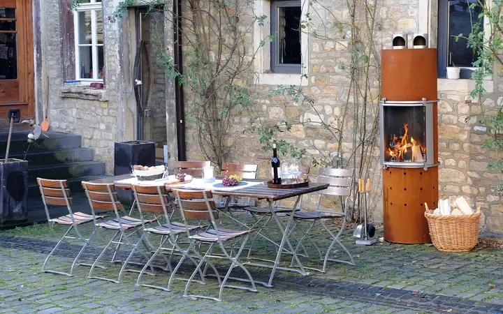Garden and chairs next to a wood-burning outdoor fire with a SCHOTT ROBAX® fire viewing panel