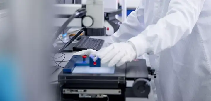 Laboratory technician operating equipment at a workstation in a cleanroom environment