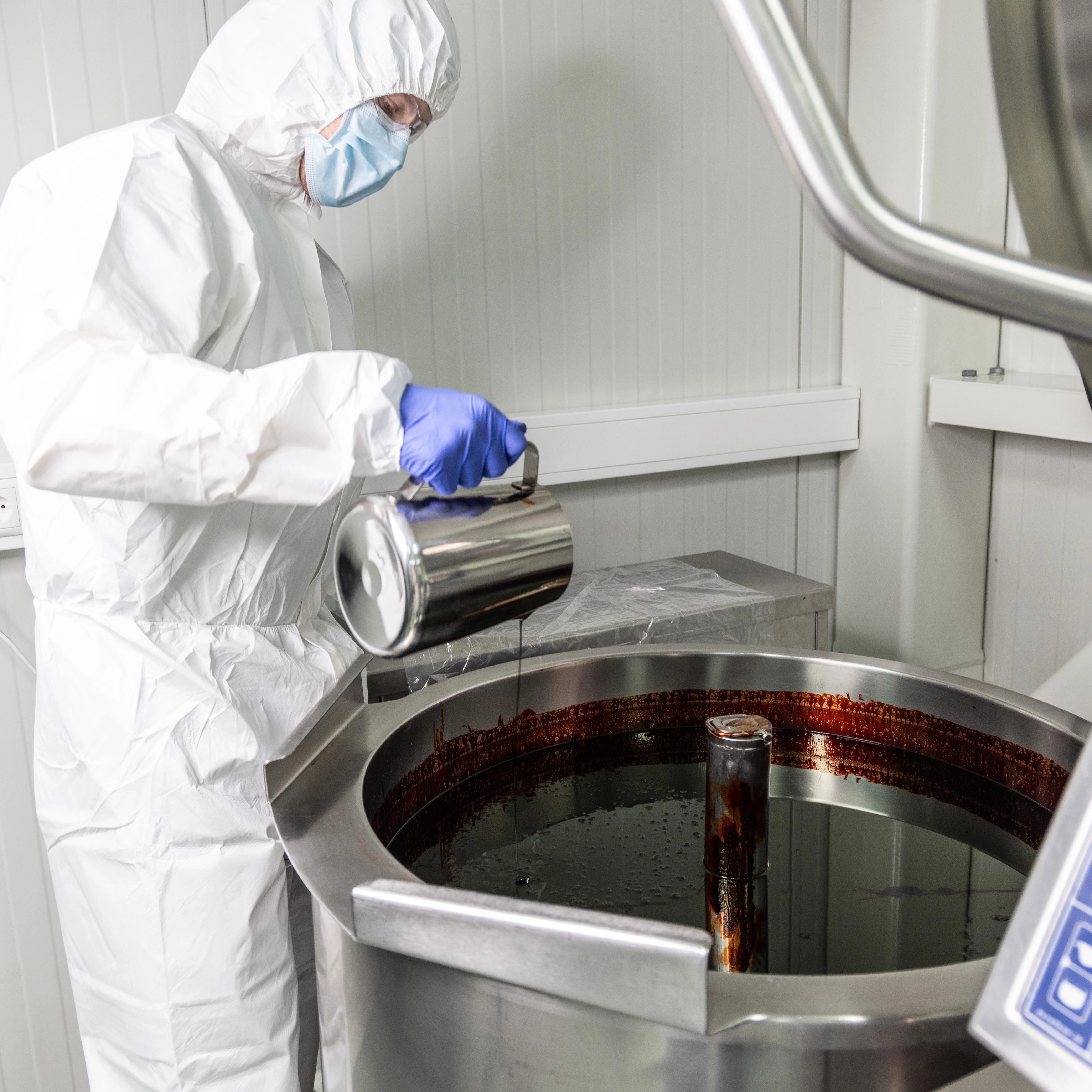 Algalif employee in protective clothing analyzing the red liquid in an open bioreactor.