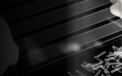 Gloved hands separate small glass parts from a frame